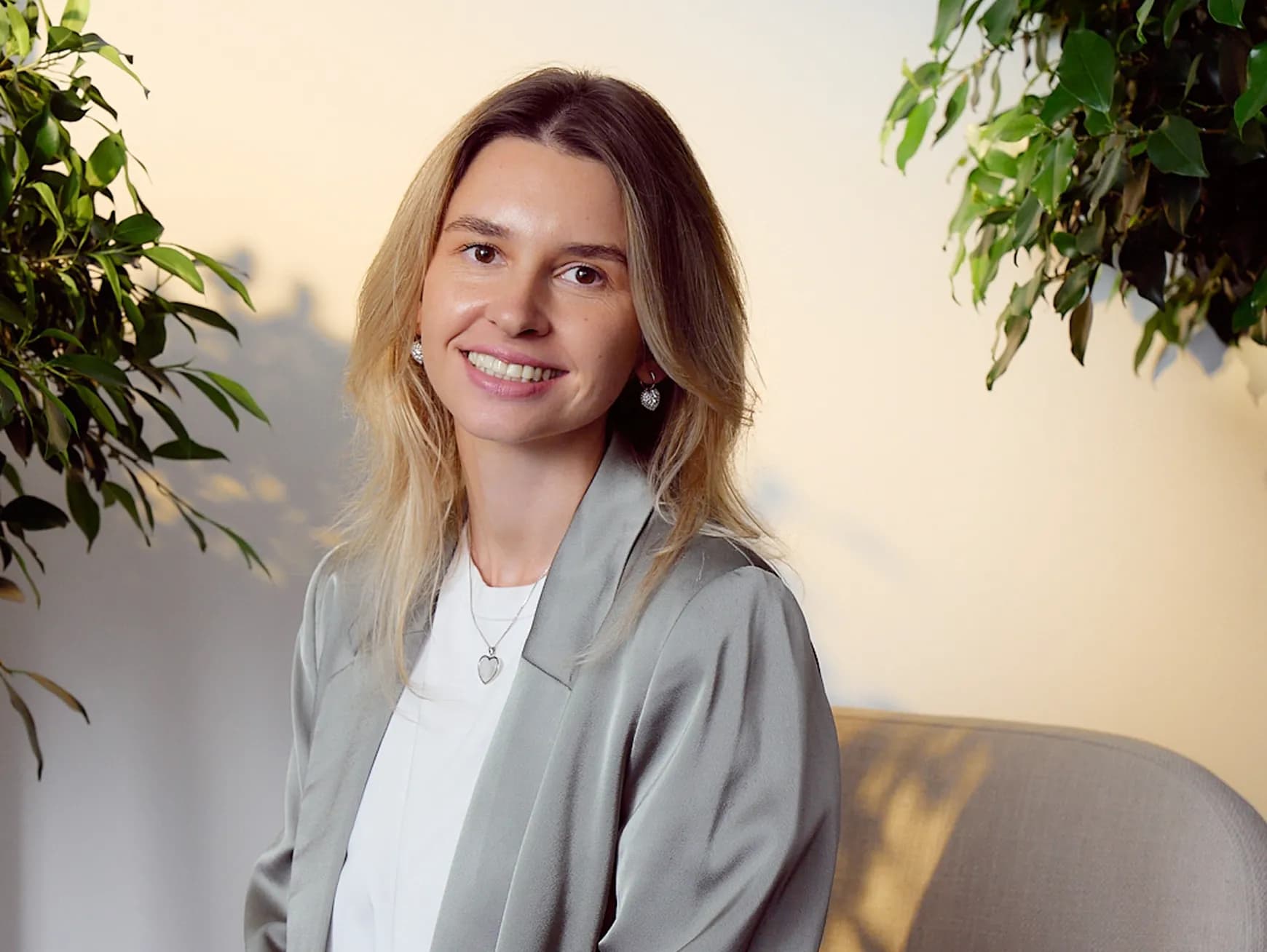 Жінка з білявим волоссям у білій футболці та сріблястому піджаку