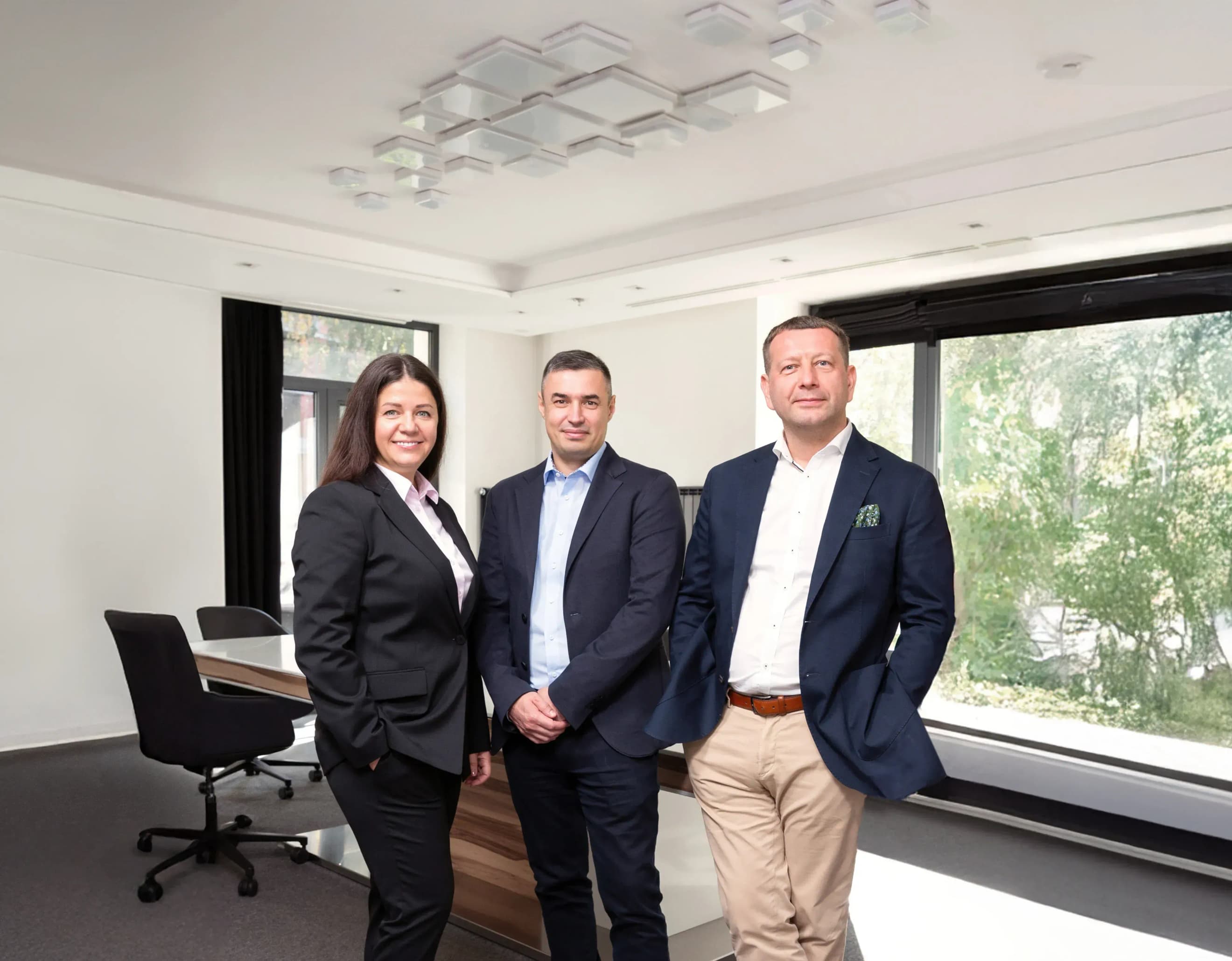 Жінка і двоє чоловіків одягнені в костюми в офісі