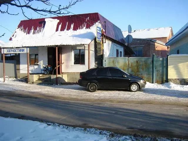 Одноповерхова будівля вздовж дороги з припаркованим автомобілем