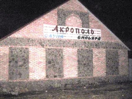 Цегляна будівля з арочними елементами та вивіскою “Акрополь”