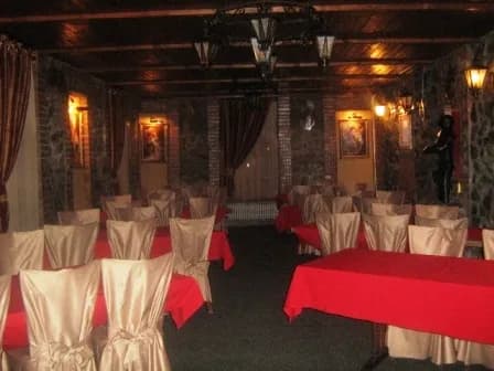 Інтер’єр із кам’яними стінами, дерев’яними балками та накритими столами