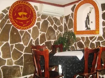 Стіл зі скатертиною біля кам’яної стіни з декоративною емблемою та настінним орнаментом