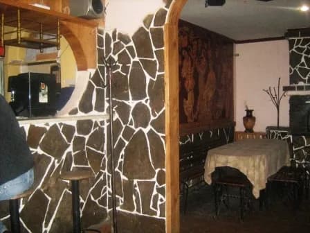 Кам’яна стіна з аркою й дерев’яними елементами поруч із накритим столом