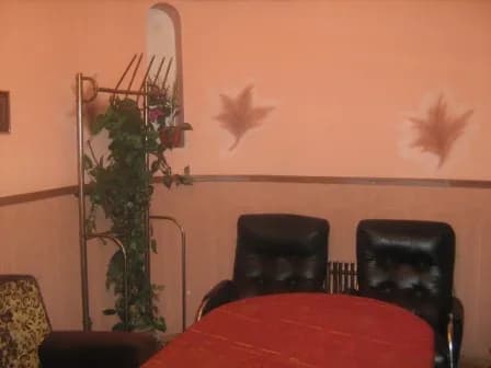 Стіл зі скатертиною поруч із кріслами та декоративною рослиною біля стіни