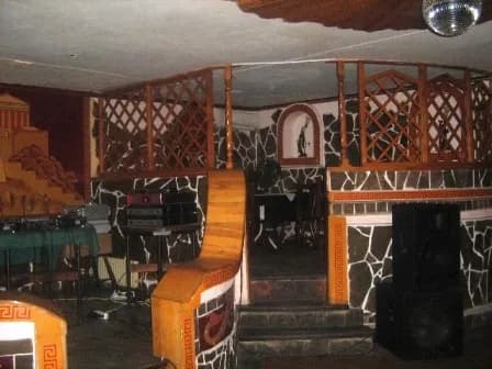 Балкон‑мезонін із дерев’яними перилами над кам’яною стіною та дверима