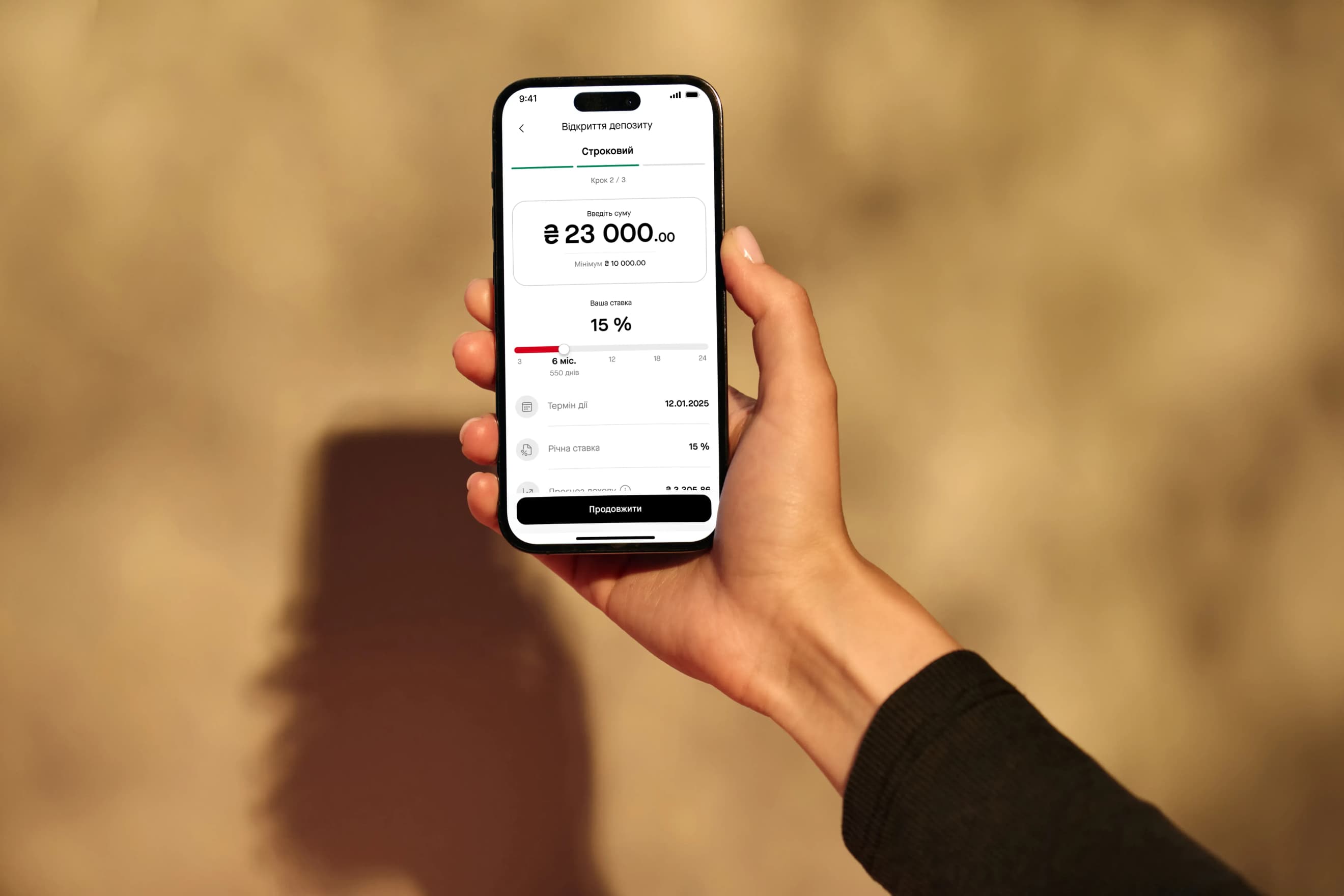 У руці телефон із відкритою сторінкою оформлення депозиту в мобільному застосунку