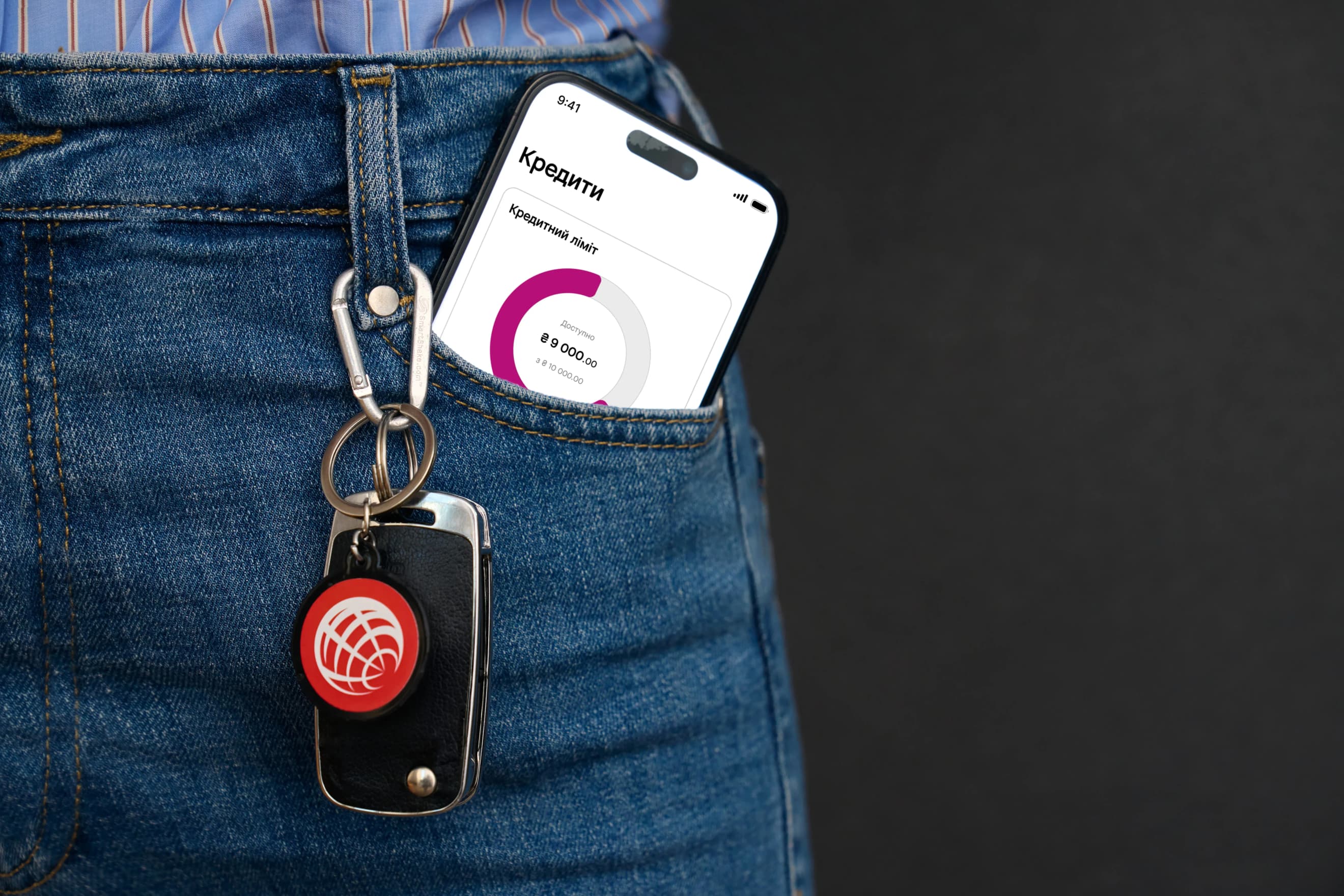 Смартфон із розділом «Кредити» застосунку ProCredit Bank стирчить із джинсової кишені поруч із брелоком для ключів