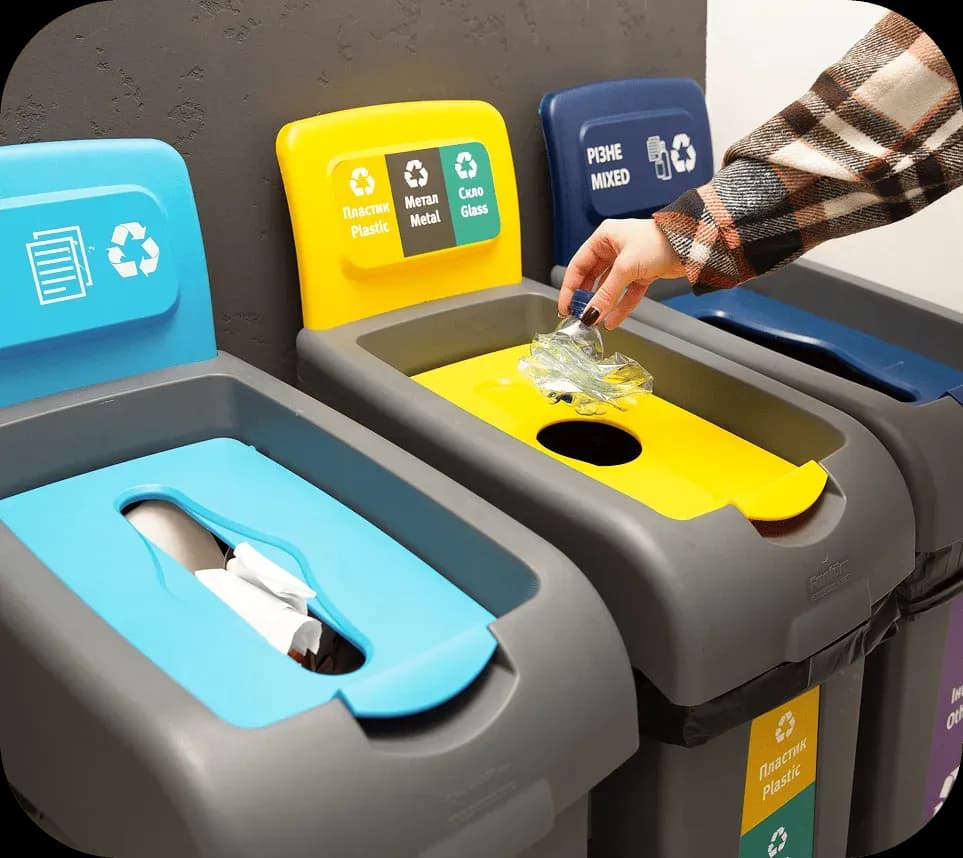 Людина викидає пластикові відходи у жовтий контейнер для роздільного збору сміття