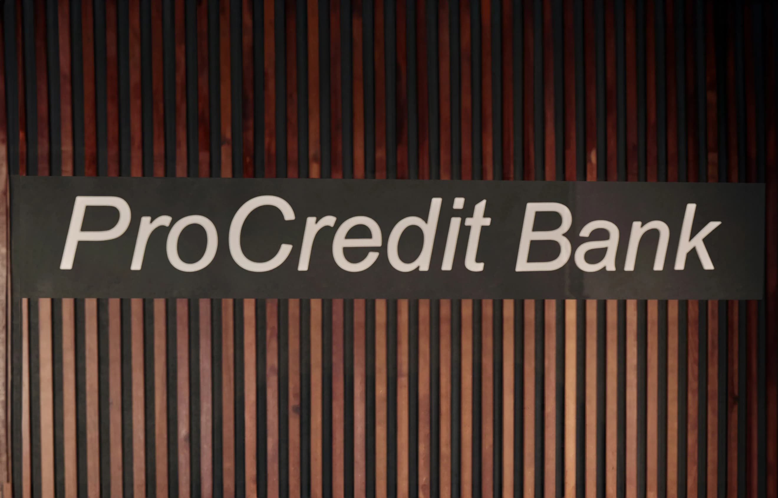 Логотип ПроКредит Банку на темній панелі з вертикальними дерев’яними рейками