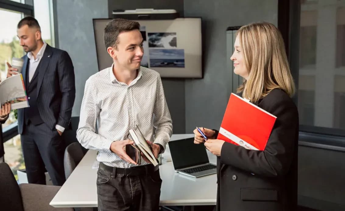 Четверо людей спілкуються парами в переговорній кімнаті біля столу з ноутбуками і документами