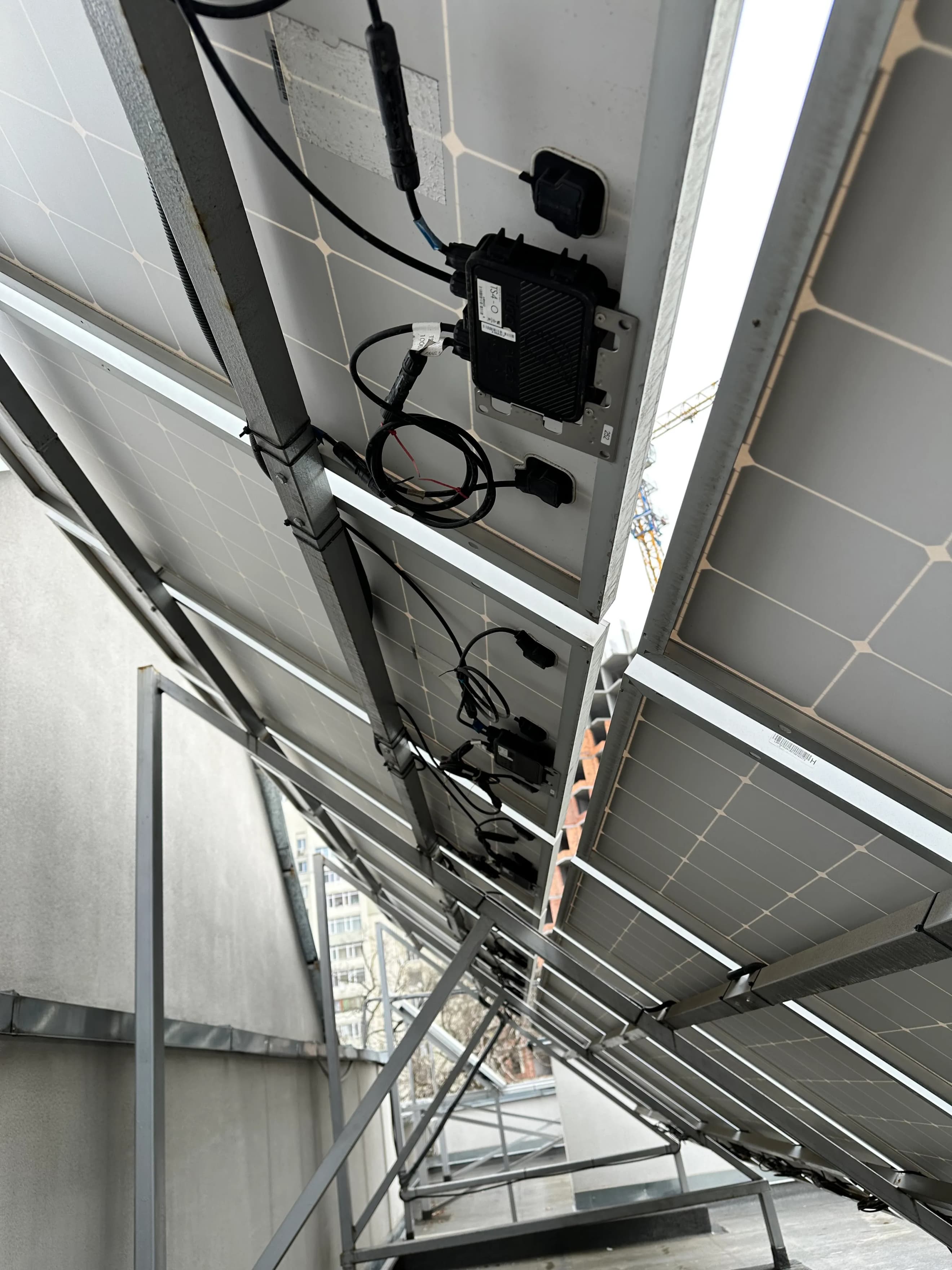 Нижня частина сонячних панелей із закріпленими кабелями та кріпленнями на металевій конструкції