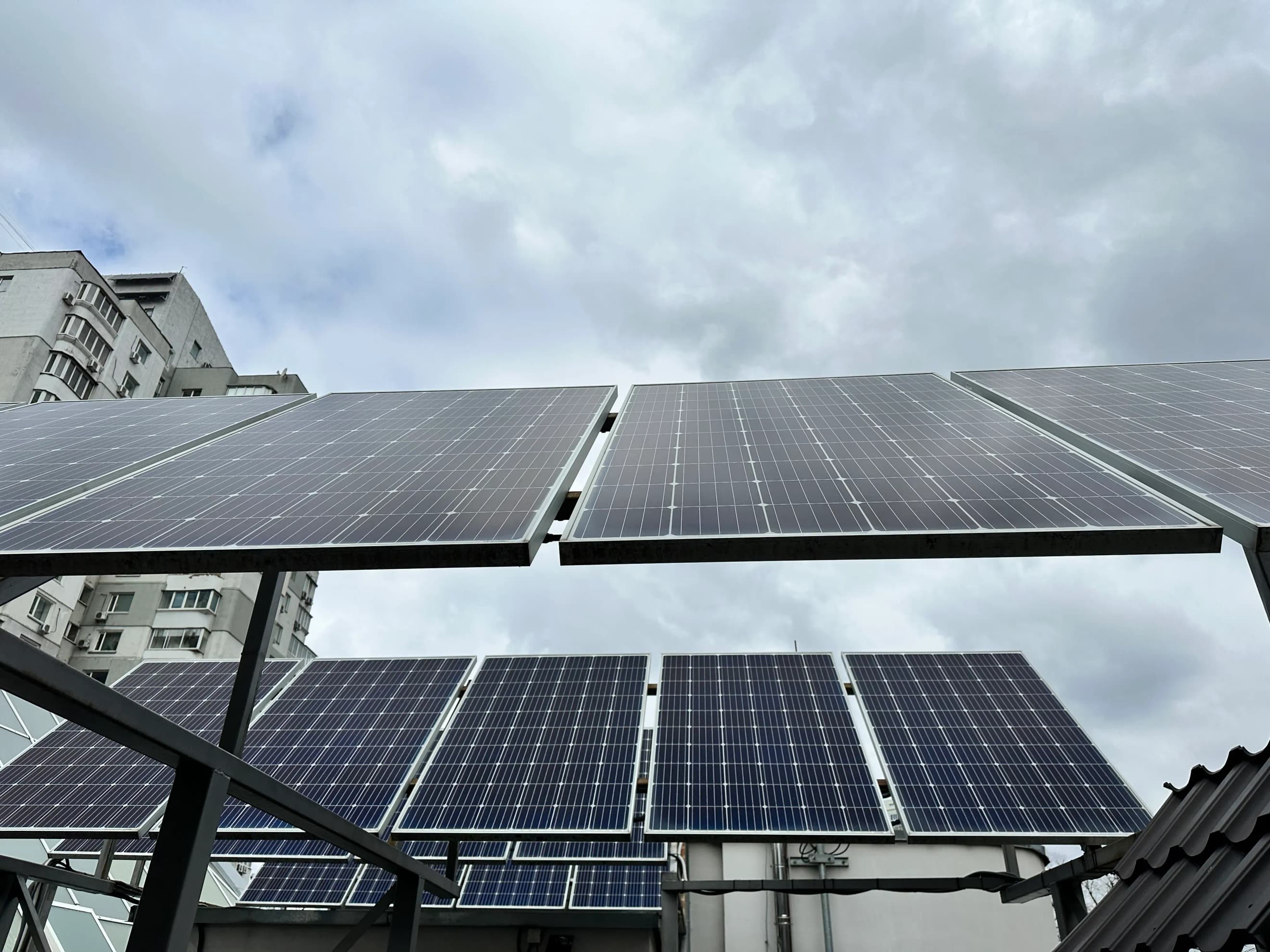 Ряди сонячних панелей, встановлених на металевій рамі на даху будівлі