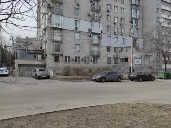 Багатоповерхова будівля вздовж дороги з припаркованими автомобілями перед фасадом