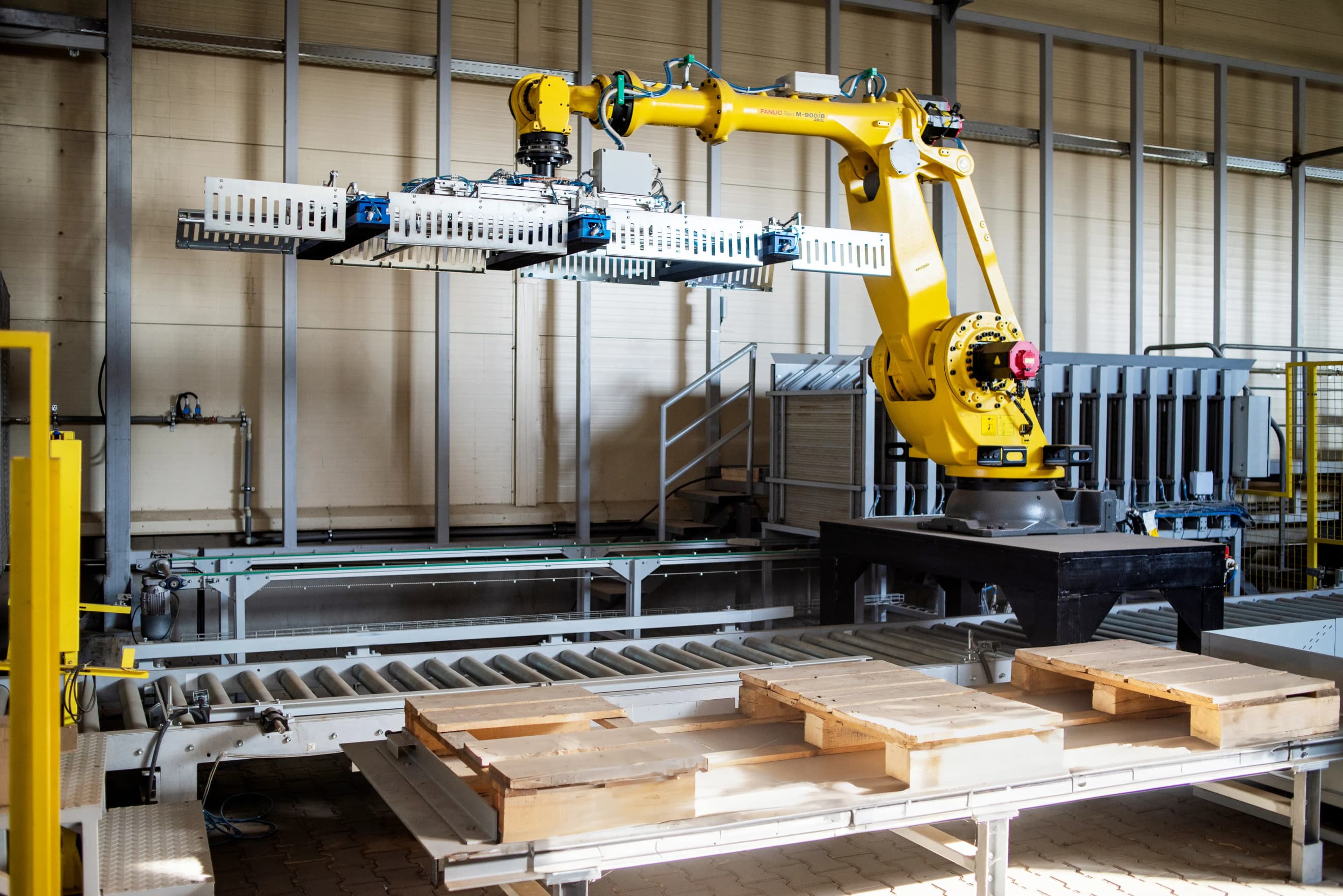 Промисловий робот‑маніпулятор працює на виробничій лінії, переміщуючи деталі над конвеєром