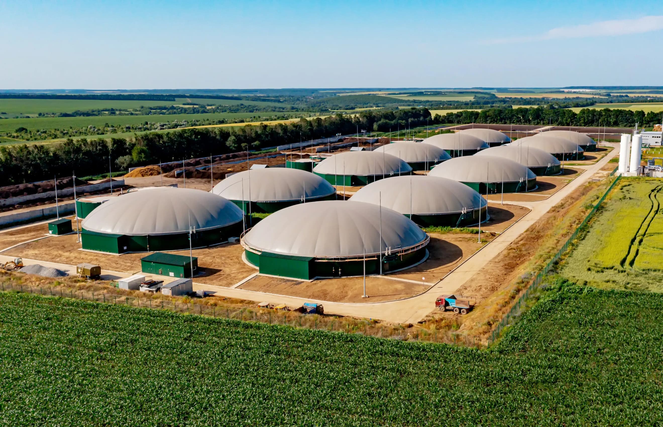 Комплекс біогазових резервуарів із круглими накриттями, розташований серед полів та зелених насаджень