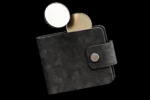 Чорний гаманець із металевою застібкою, з якого виглядають дві золотисті монети