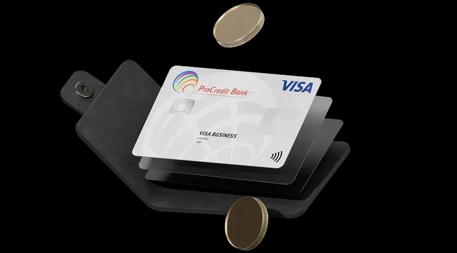 Корпоративна картка та монети, розміщені в розкритому чорному гаманці