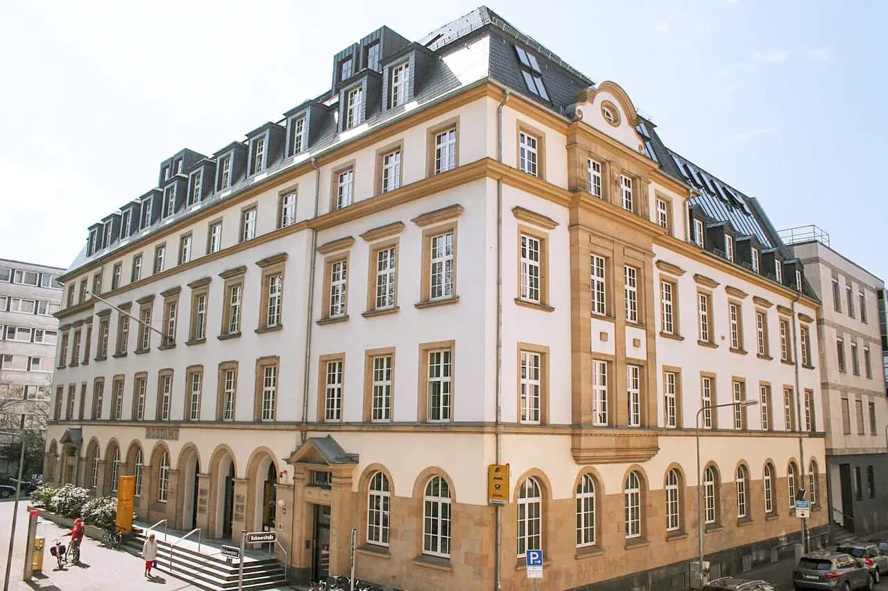 Будівля Головного офісу банку в Німеччині з великими вікнами та світлим фасадом на розі вулиці